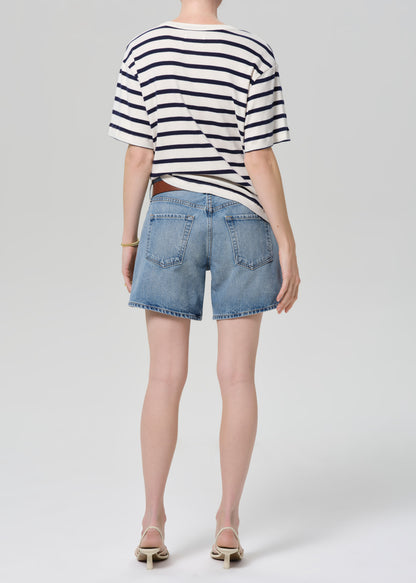 Person wearing a striped shirt and denim shorts on a plain background