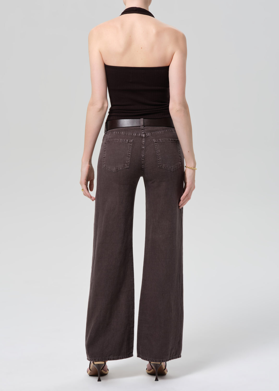 Person wearing a dark brown halter top and charcoal wide-leg linen pants on a plain background 