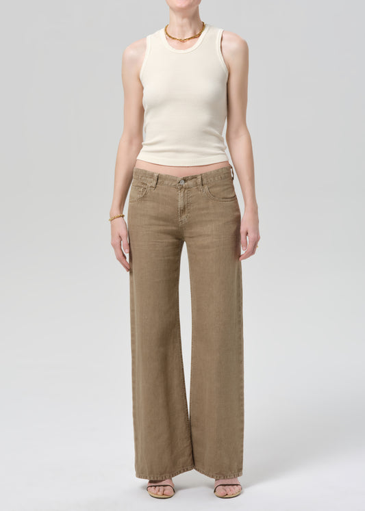 Person wearing a off-white sleeveless top and wide-leg brown linen pants on a plain background