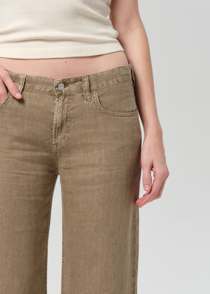 Person wearing a off-white sleeveless top and wide-leg brown linen pants on a plain background