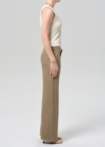 Person wearing a off-white sleeveless top and wide-leg brown linen pants on a plain background