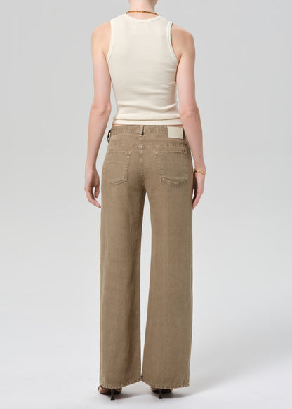 Person wearing a off-white sleeveless top and wide-leg brown linen pants on a plain background