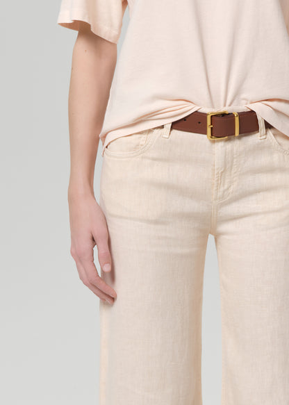Person wearing a light peach top and off-white linen wide-leg pants on a plain background