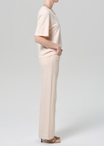 Person wearing a light peach top and off-white linen wide-leg pants on a plain background