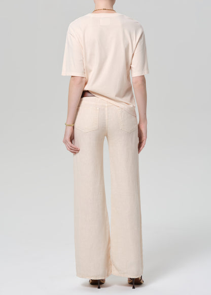 Person wearing a light peach top and off-white linen wide-leg pants on a plain background