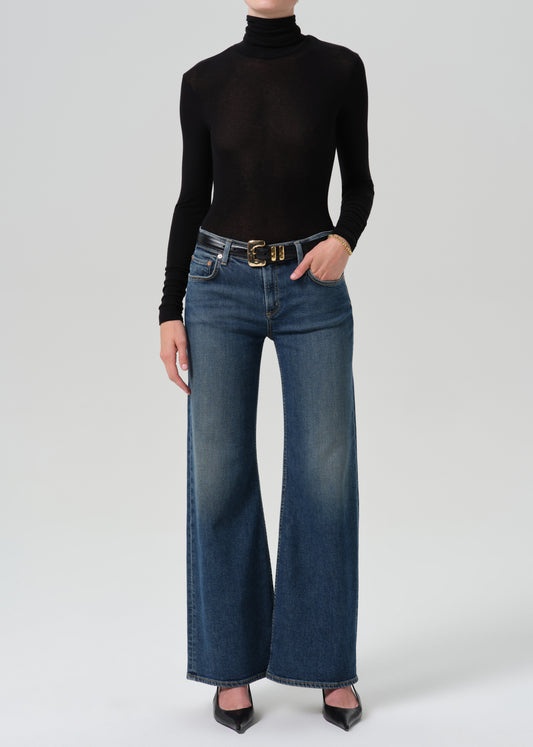 Person wearing black turtleneck with a blue pant on a grey background