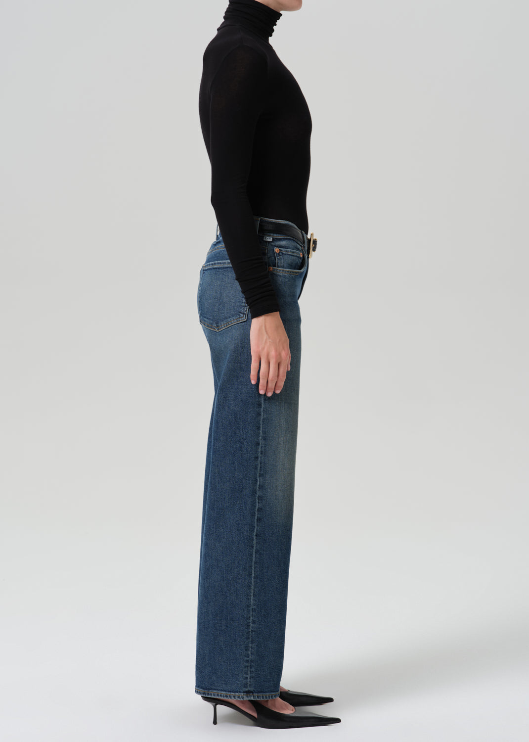 Person wearing black turtleneck with a blue pant on a grey background