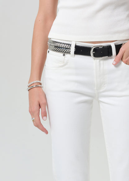Person wearing white pants with a black belt and silver accents on a plain background
