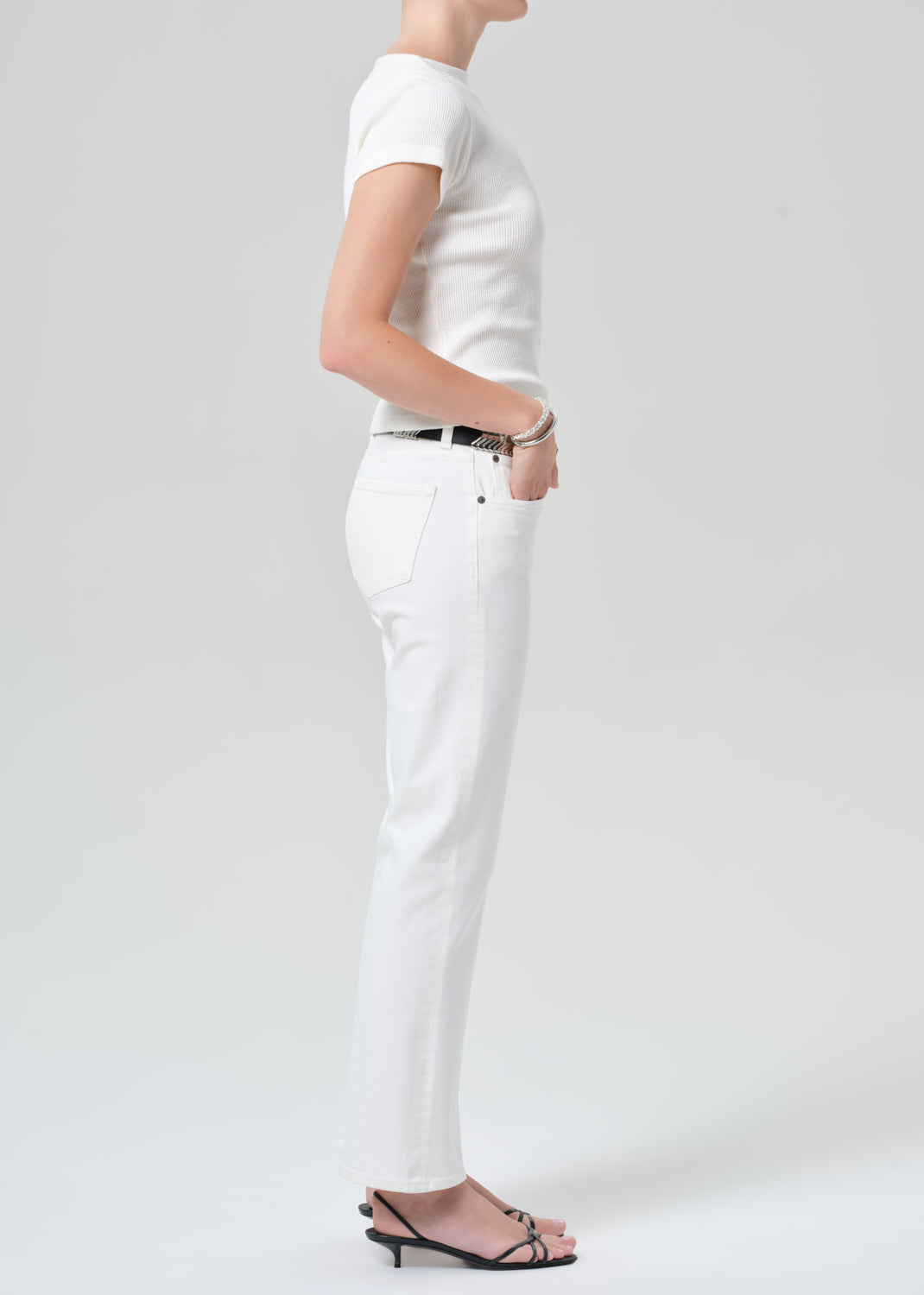 Person wearing a white t-shirt and white pants on a plain background