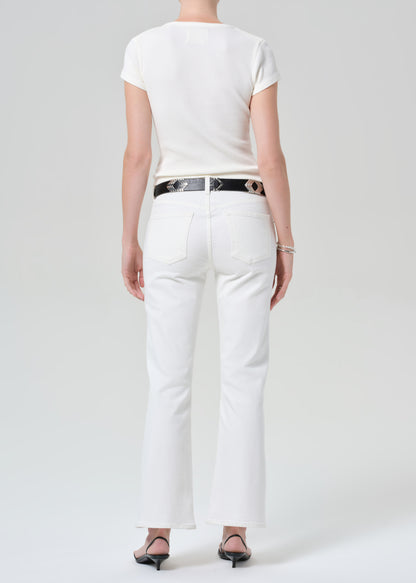 Person wearing a white top and white pants with a black belt on a plain background