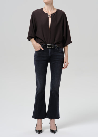 Person wearing a brown shirt with dark blue pants on a grey background