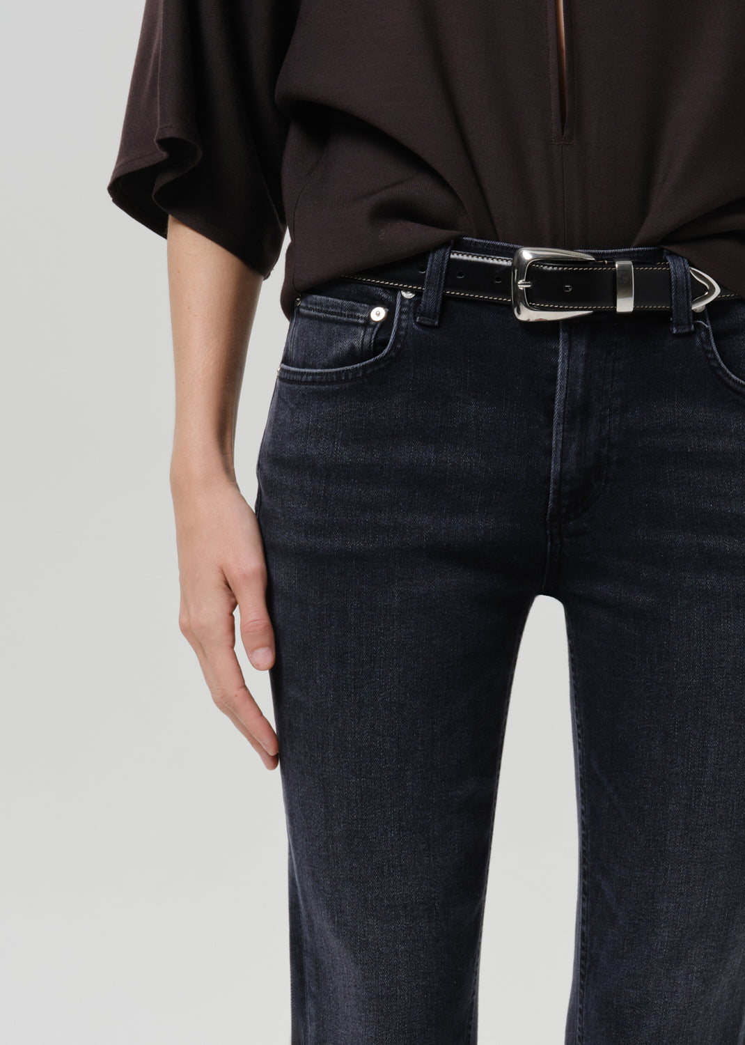 Close up of brown shirt on blue jeans on a grey background