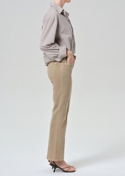 Person wearing a light gray button-up shirt and beige jean on a grey background