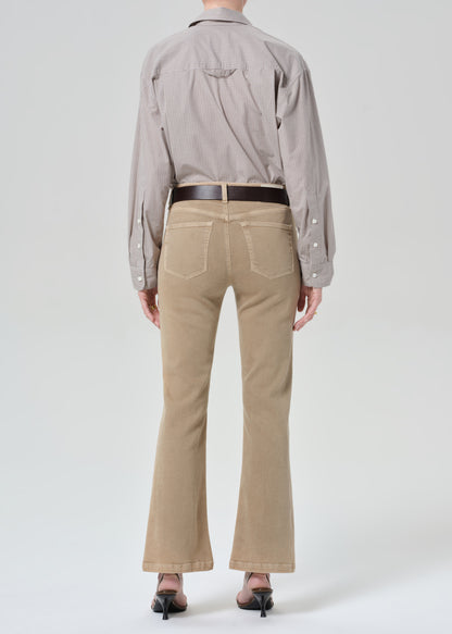 Person wearing a light gray button-up shirt and beige jean on a grey background