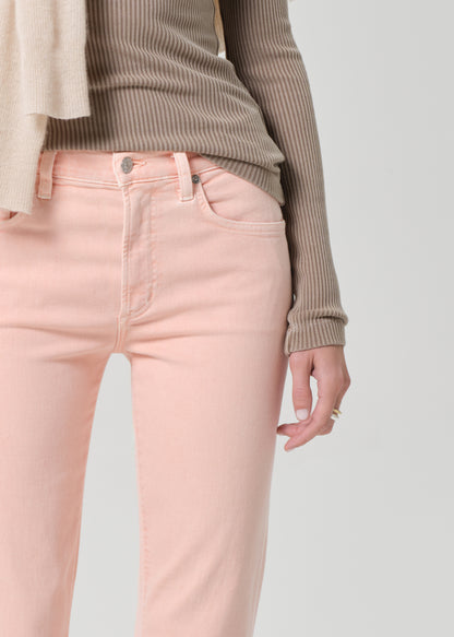 Person wearing a brown top and pink jeans on a grey background