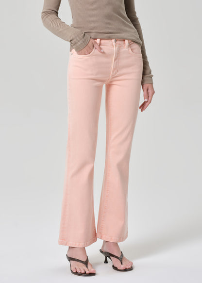 Person wearing a brown top and pink jeans on a grey background