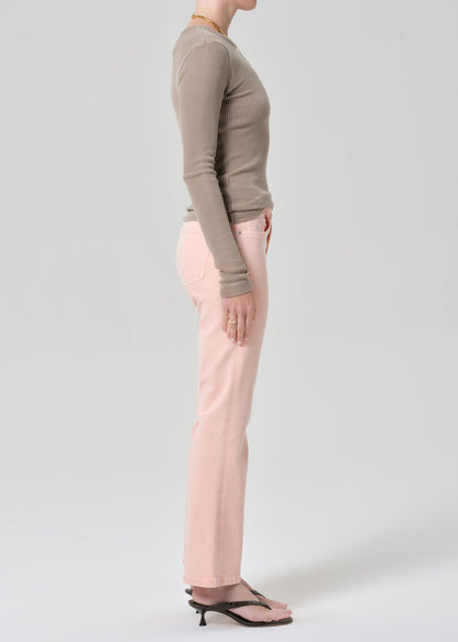 Person wearing a brown top and pink jeans on a grey background