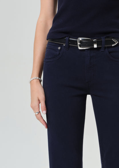 Person wearing a navy t-shirt and dark navy jeans on a grey background