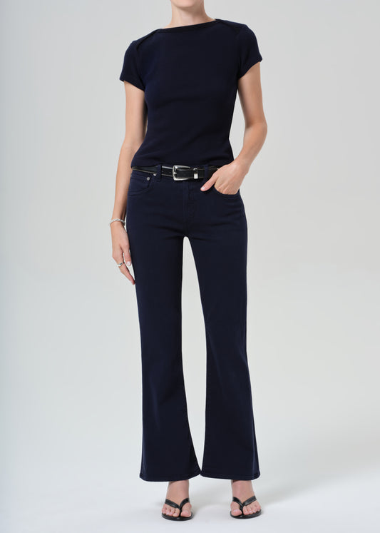 Person wearing a navy t-shirt and dark navy jeans on a grey background