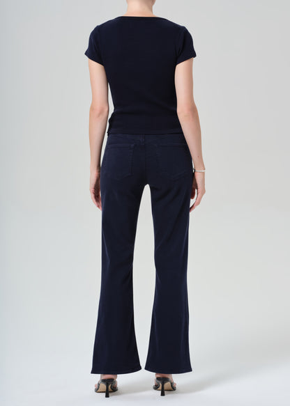 Person wearing a navy t-shirt and dark navy jeans on a grey background