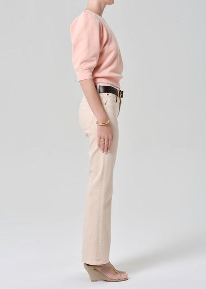 Person wearing a pink sweatshirt and light pink jeans on a grey background