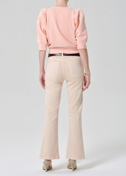 Person wearing a pink sweatshirt and light pink jeans on a grey background