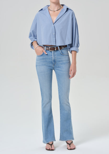 Person wearing a light blue plaid shirt and jeans on a grey background