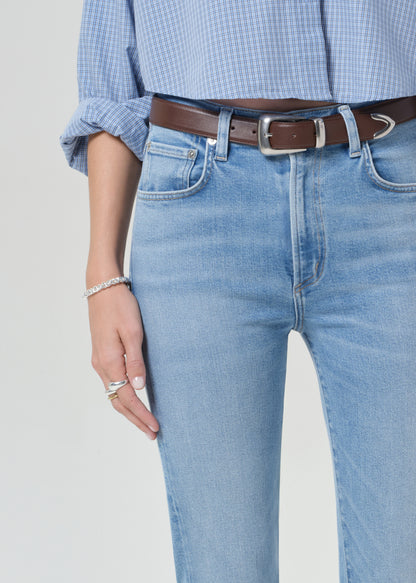 Person wearing a light blue plaid shirt and jeans on a grey background