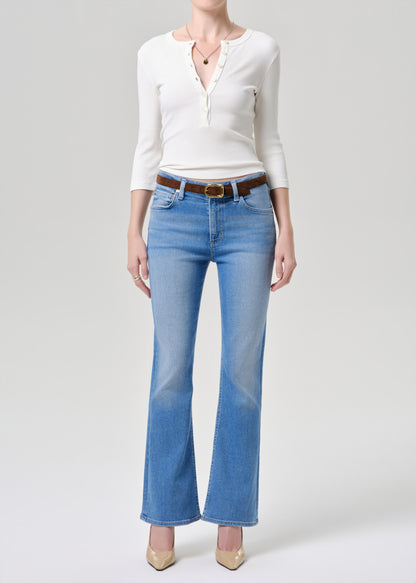 Person wearing a white blouse and blue jeans on a grey background