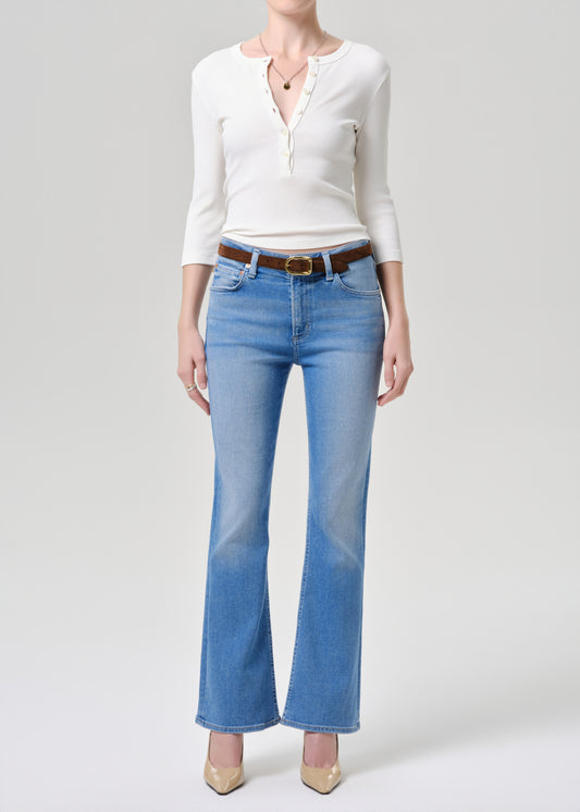 Person wearing a white blouse and blue jeans on a grey background