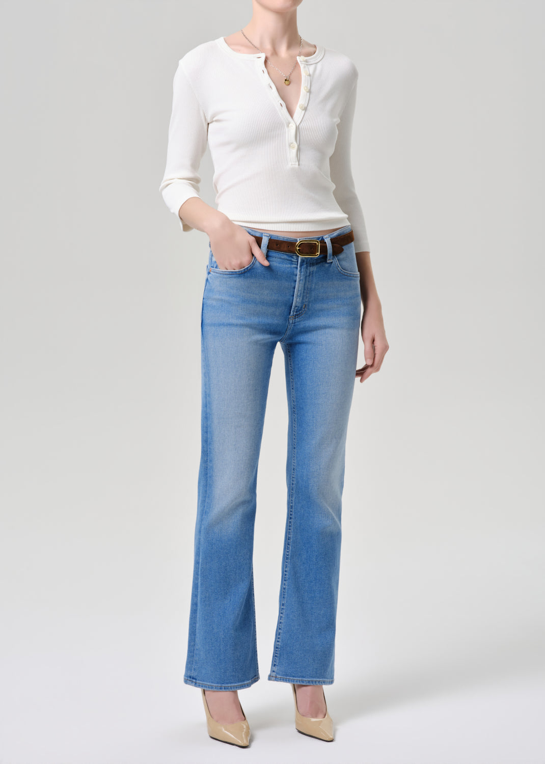 Person wearing a white shirt and blue jeans on a grey background
