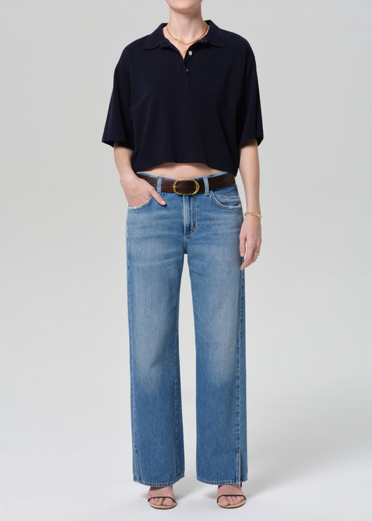 Person wearing a navy polo shirt and blue jeans on a light gray background