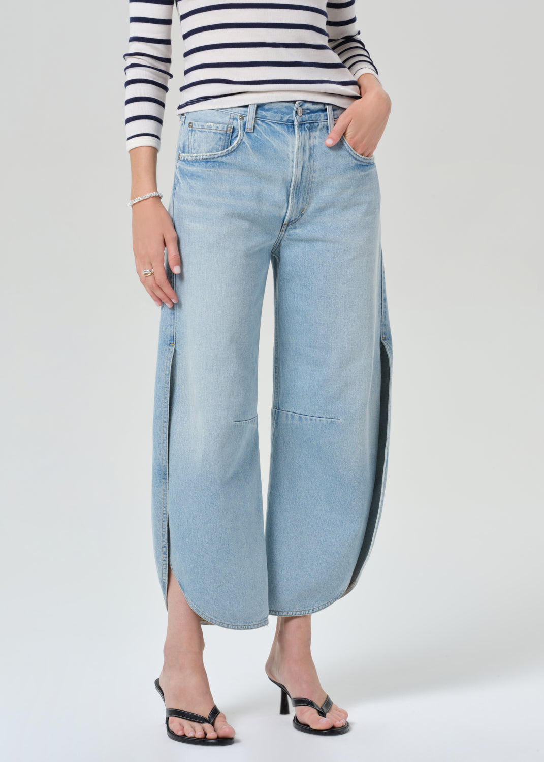 Person wearing a navy and white striped shirt and light blue wide-leg jeans on a grey background