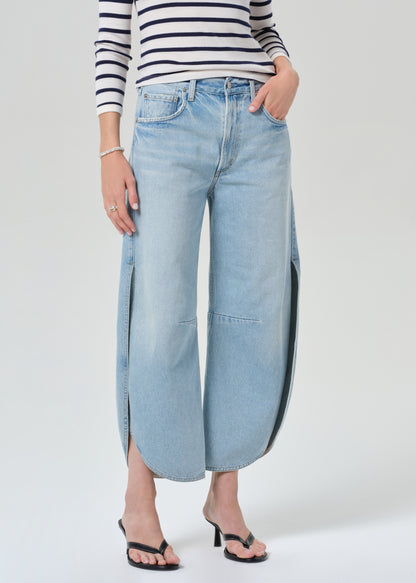 Person wearing a navy and white striped shirt and light blue wide-leg jeans on a grey background