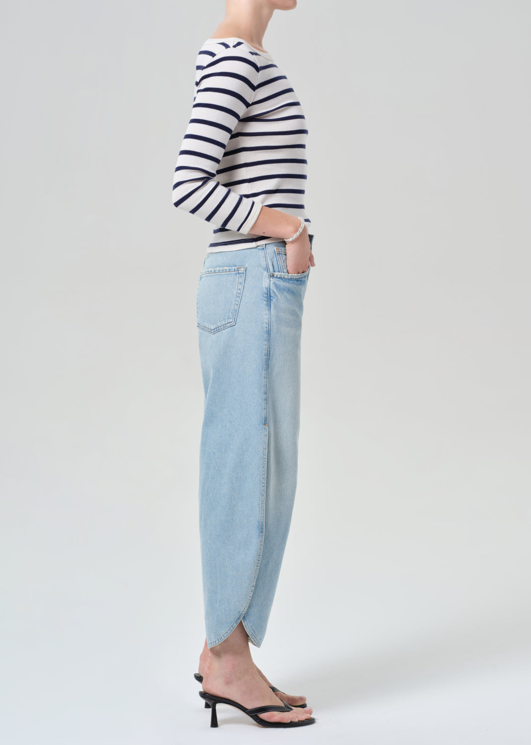 Person wearing a navy and white striped shirt and light blue wide-leg jeans on a grey background