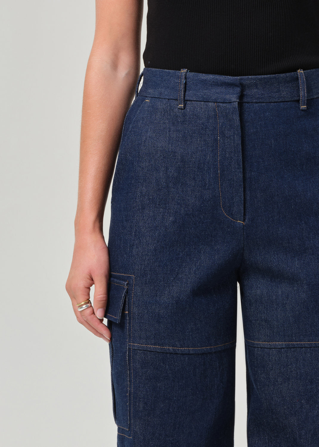 Person wearing dark blue denim cargo pants on a plain background