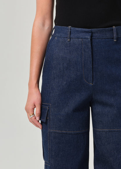 Person wearing dark blue denim cargo pants on a plain background