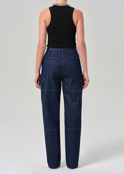 Person wearing dark blue jeans and a black sleeveless top on a light gray background