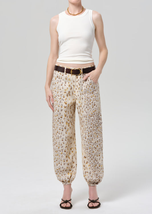 Person wearing a white sleeveless top and leopard pants on a grey