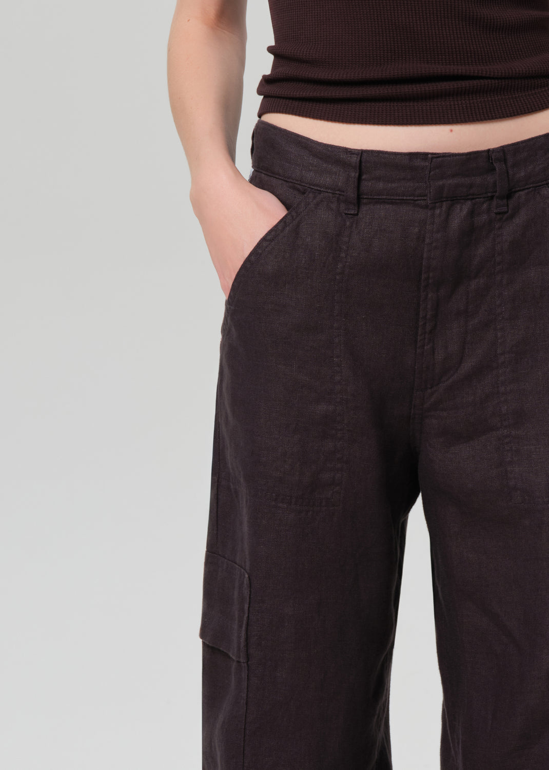 Person wearing a brown tee and charcoal pants on a plain background