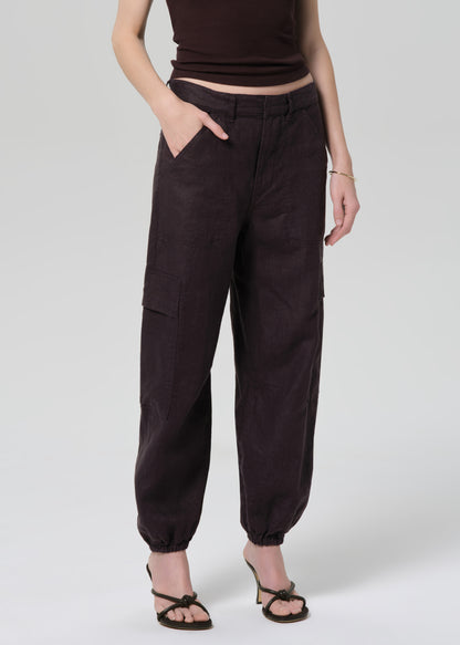 Person wearing a brown tee and charcoal pants on a plain background