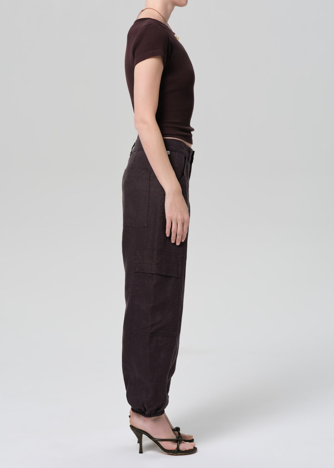 Person wearing a brown tee and charcoal pants on a plain background