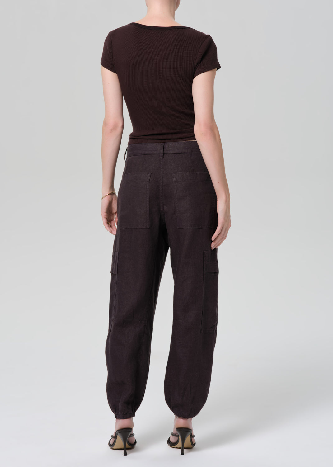 Person wearing a brown tee and charcoal pants on a plain background