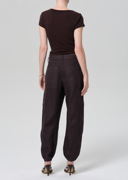 Person wearing a brown tee and charcoal pants on a plain background