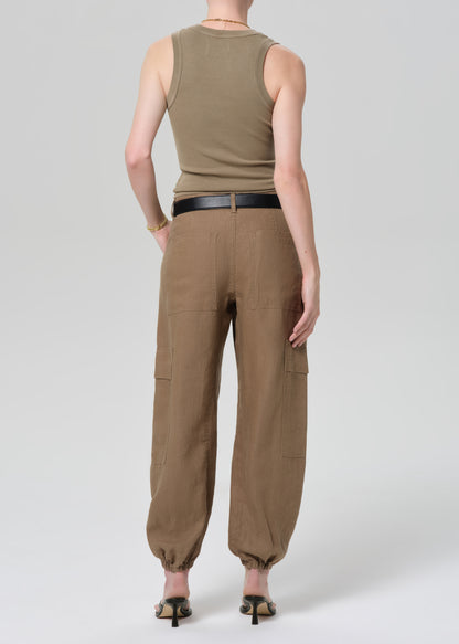 Person wearing a sleeveless olive green top and brown cargo pants on a plain background