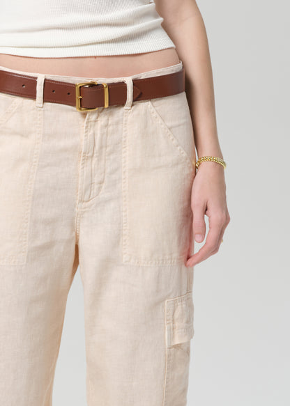 Person wearing beige cargo pants with a brown belt on a light gray background