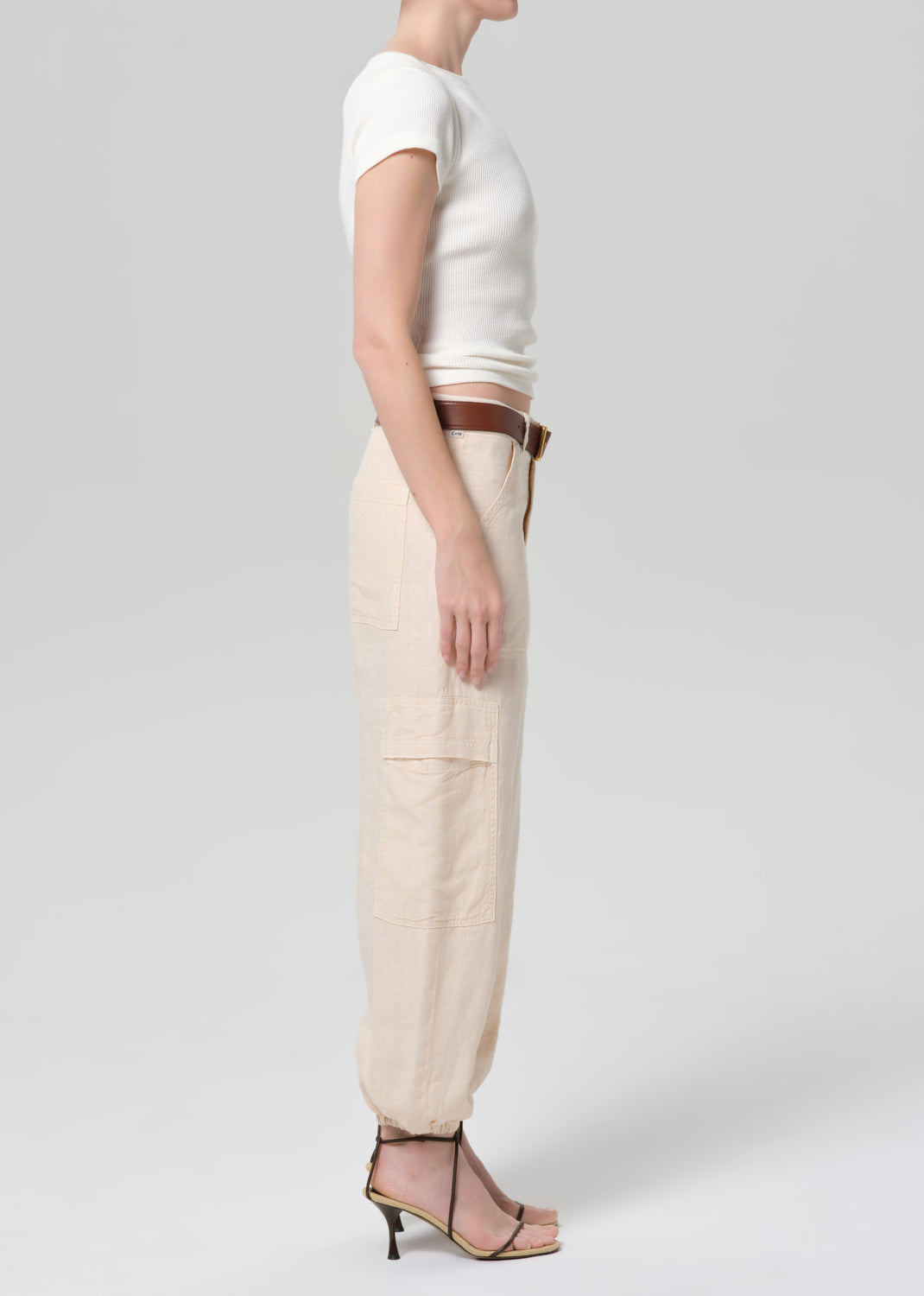Person wearing a white top and beige pants on a plain background