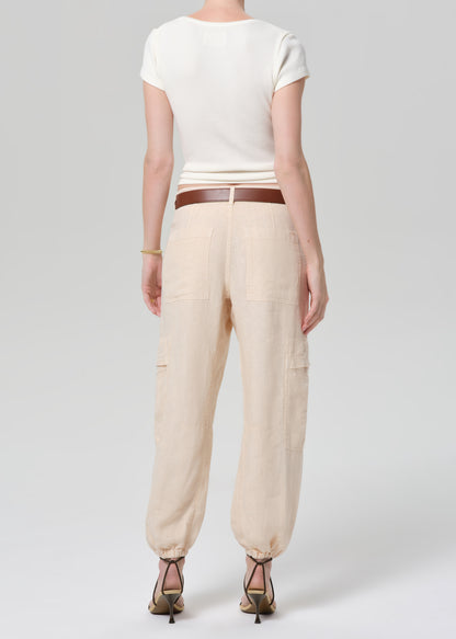 Person wearing a white top and beige pants on a plain background