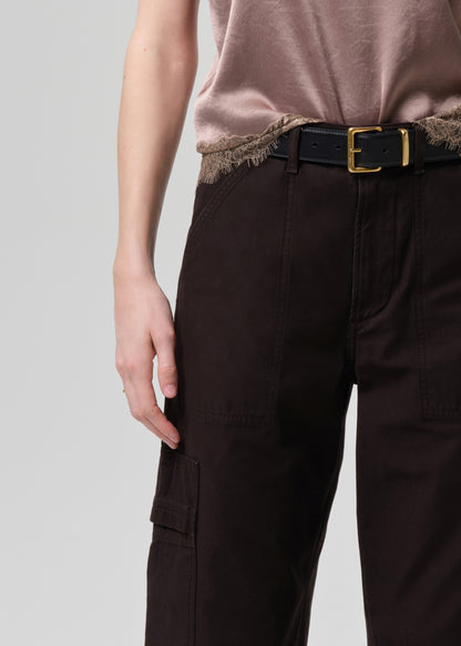 Person wearing brown cargo pants with a belt on a grey background