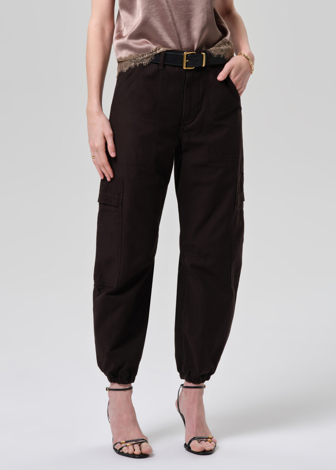 Person wearing black cargo pants on a grey background